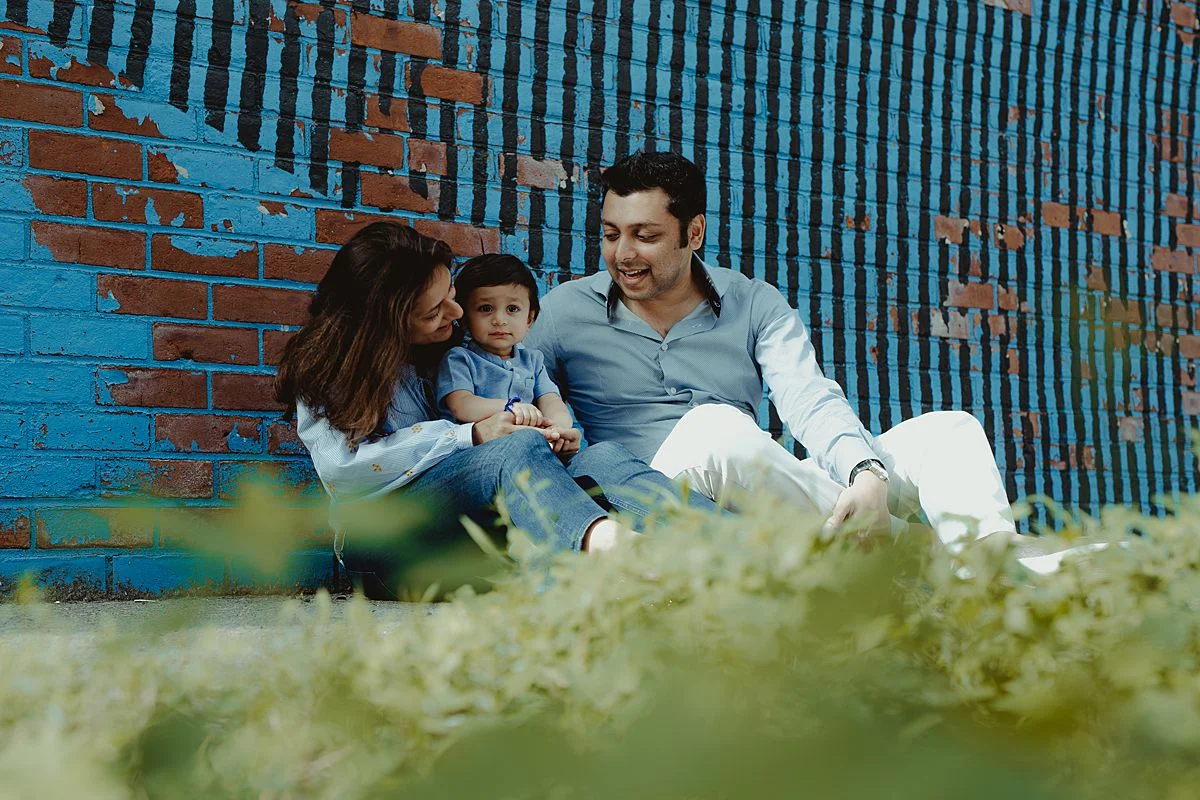 dad, mom and son sit playing together in front of brooklyn grafitti mural. image by nyc family and newborn photographer krystil mcdowall