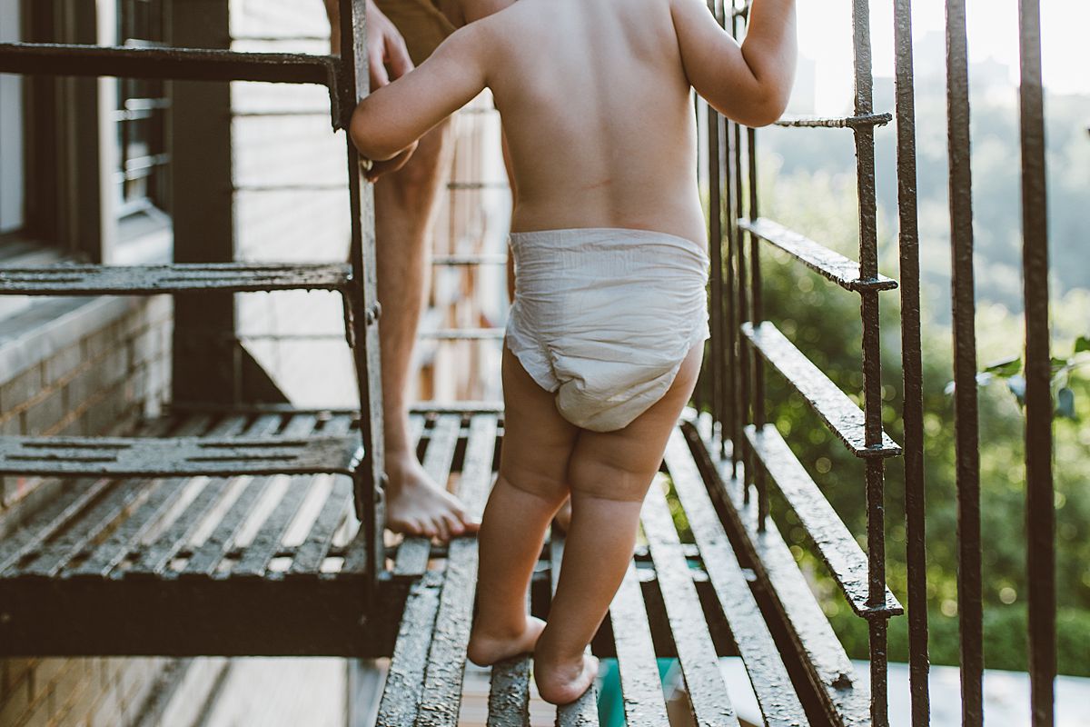 details shot of dad and son feet while playing on the fire escape outside of their nyc apartment