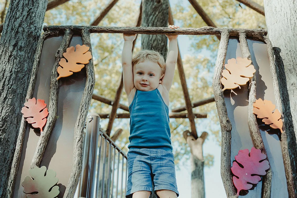 son swings at the top of the slide at discovery park in nyc during family lifestyle session