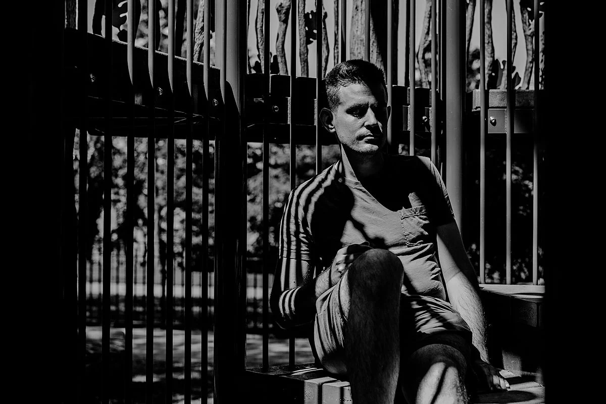 black and white image of dad enjoying quiet peaceful moment in the sun in the playground