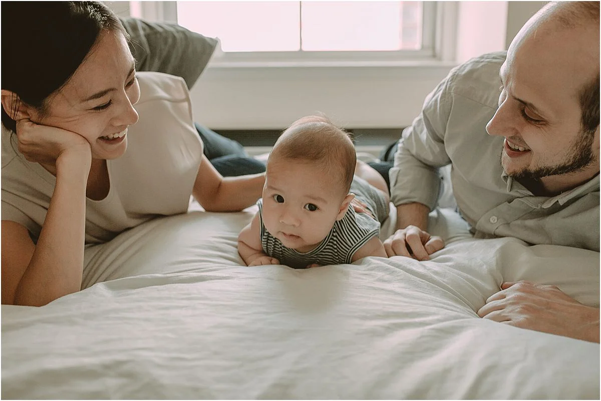 mom, dad and son lay on bed for tummy time. image by family nyc family photographer krystil mcdowall