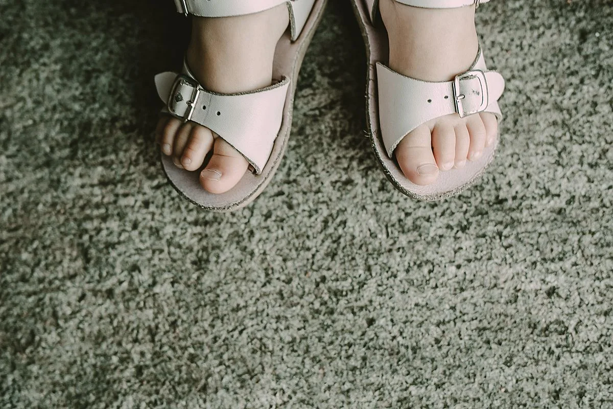 close up photo of daughter's feet in cute white sandlas. photo by nyc family and newborn photographer krystil mcdowall