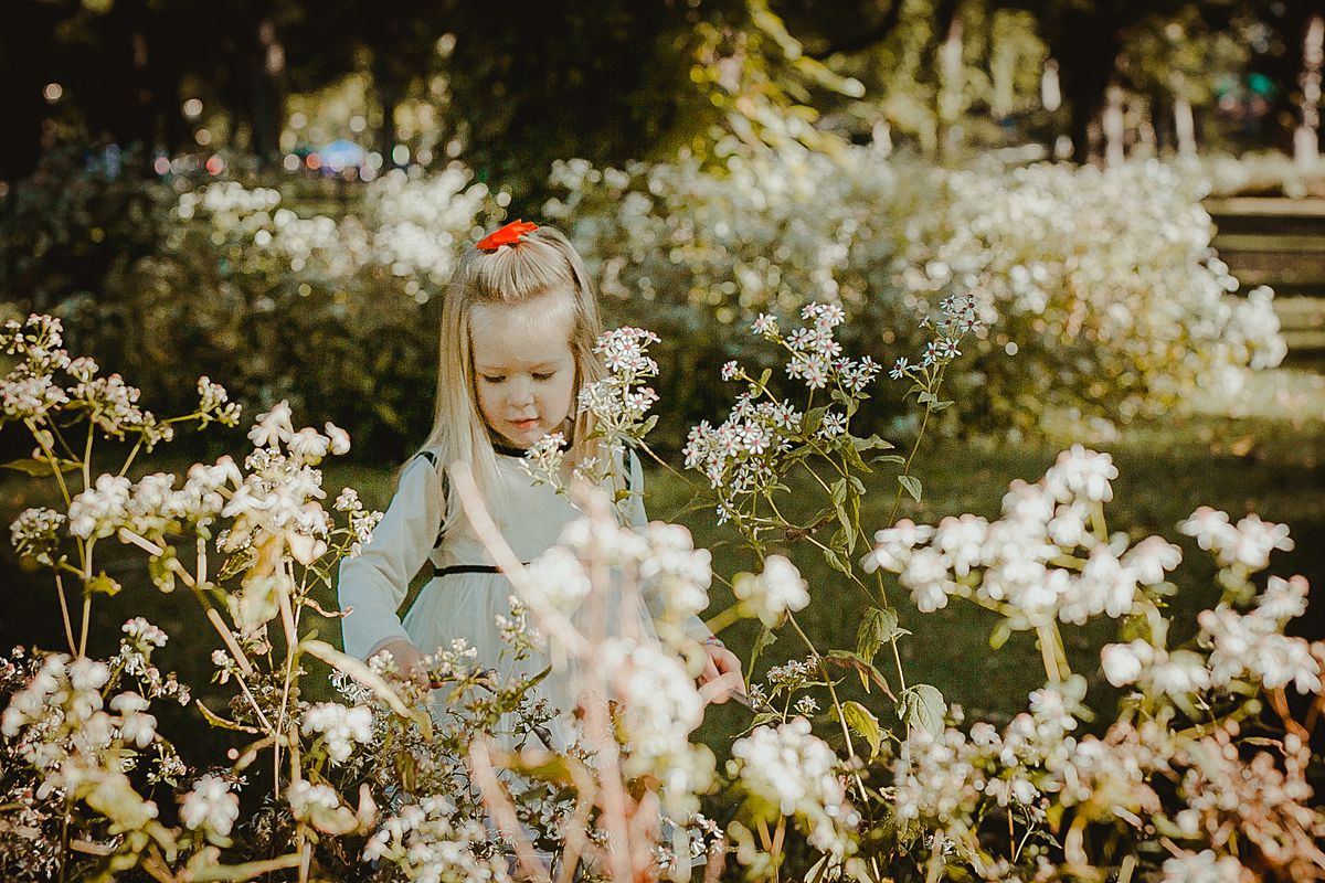 young girl playing amongst white flowers in central park new york city