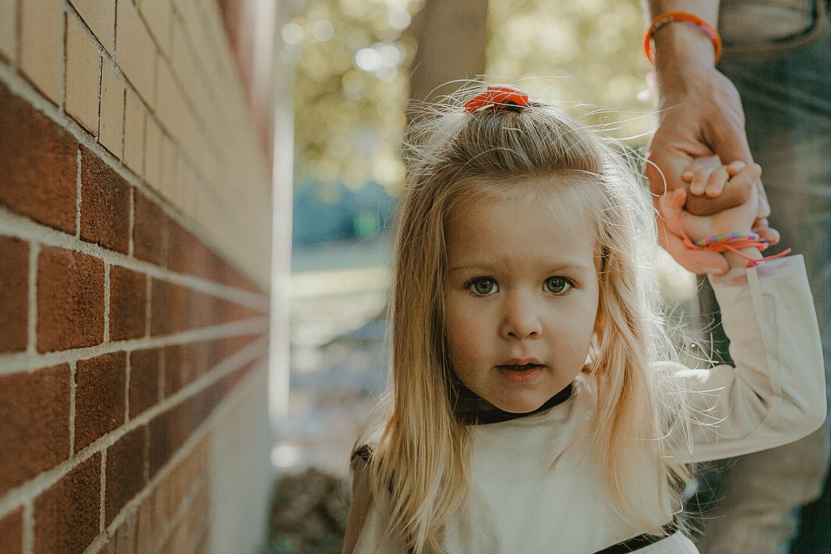 portrait of young girl as she explores the nooks and crannies of central park nyc during candid family photo session