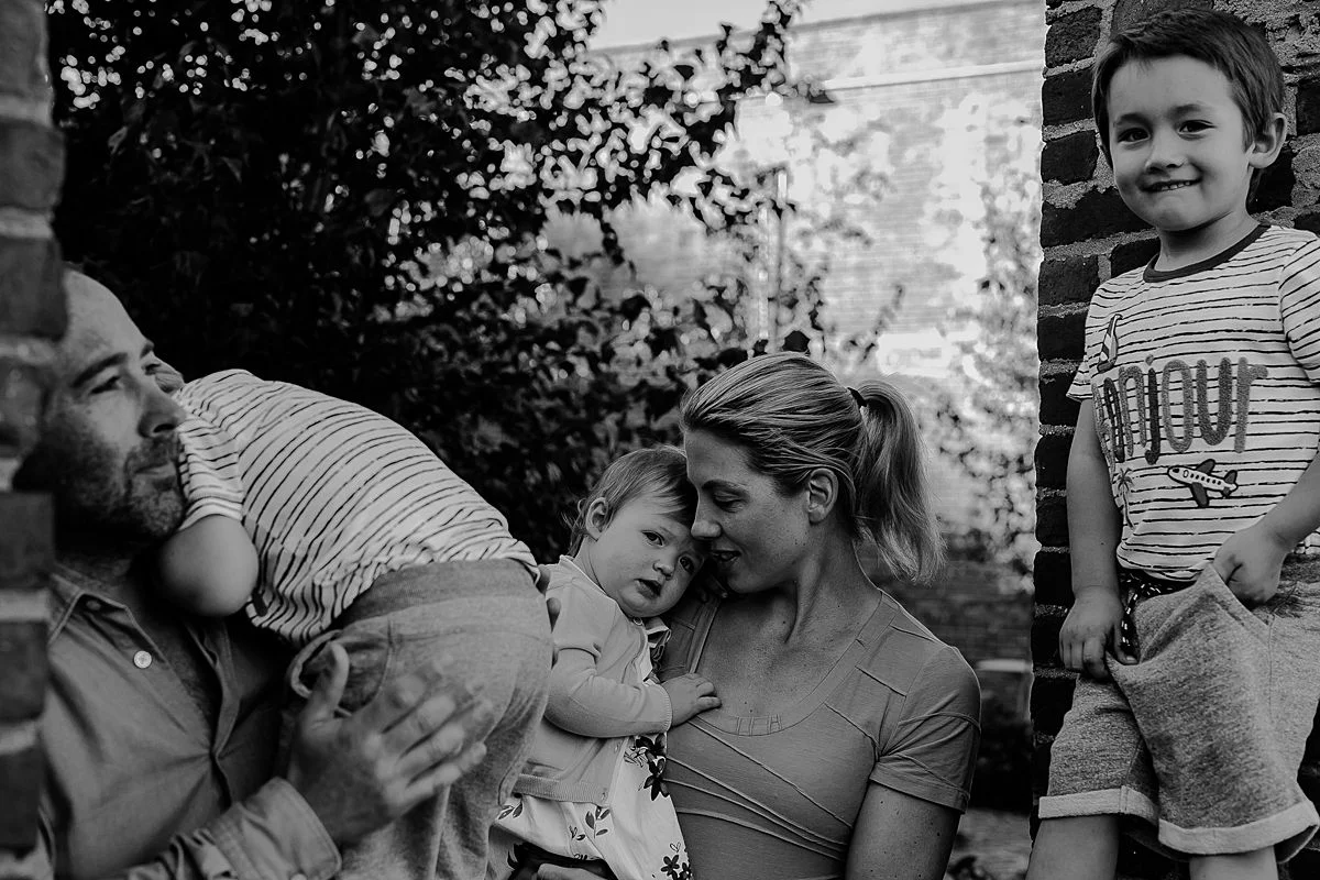 family sits in brick wall window looking out at the east river during candid fun family session with krystil mcdowall photography