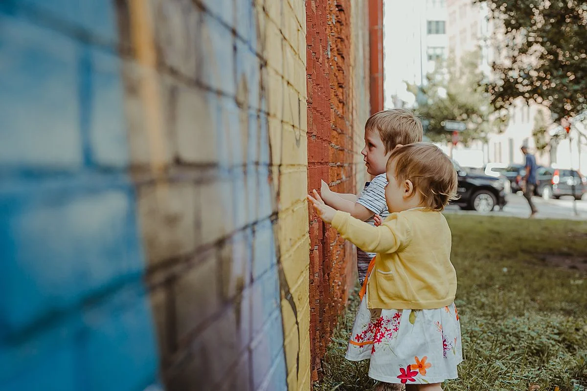 siblings explore colorful graffiti wall in dumbo brooklyn. image by nyc family photographer krystil mcdowall