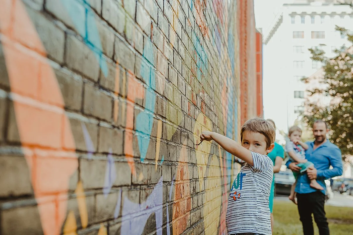 boy plays with sticks against graffiti wall in dumbo brooklyn. image by nyc family photographer krystil mcdowall