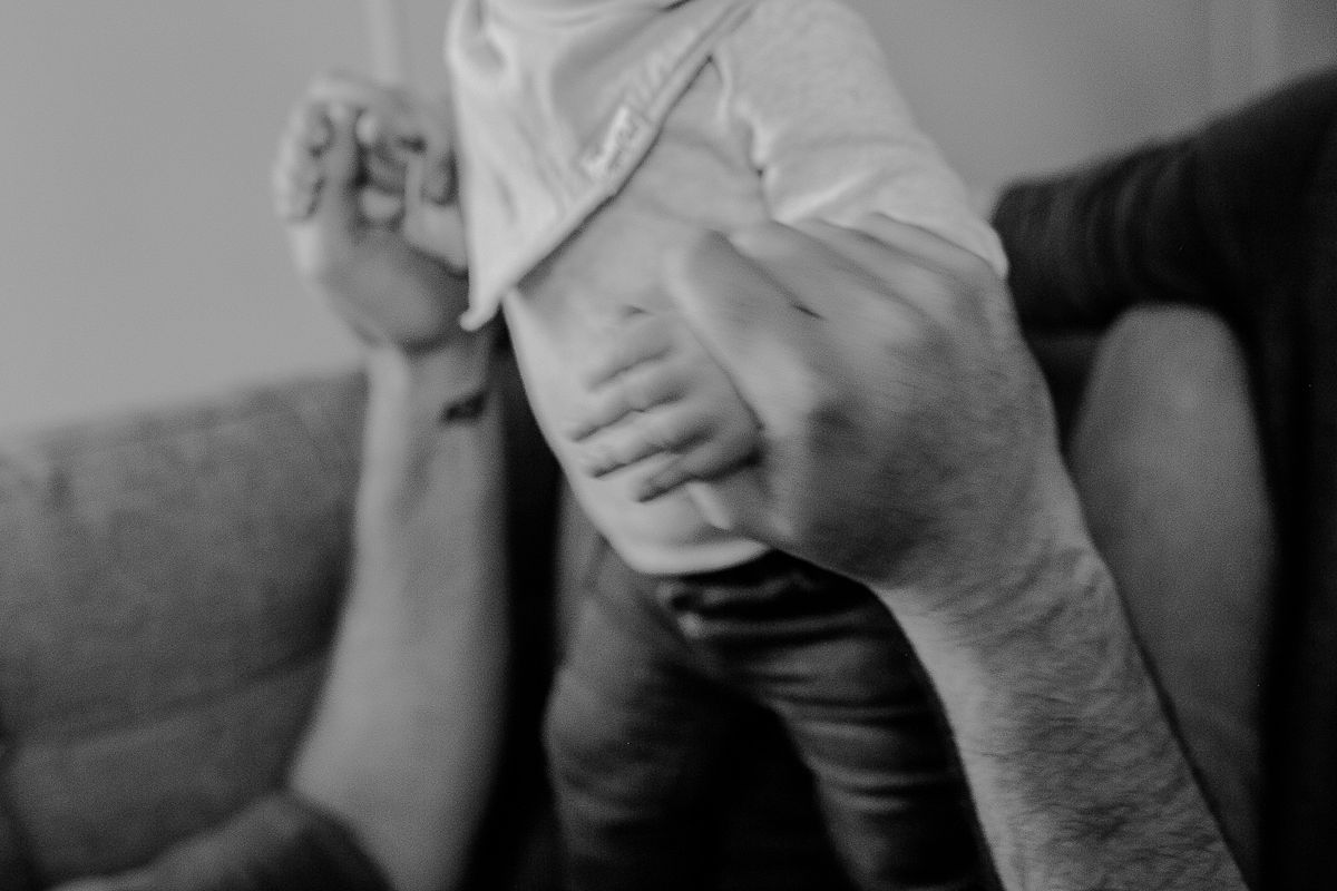 black and white close up photo of dad holding babies hands. photo by nyc family photographer krystil mcdowall