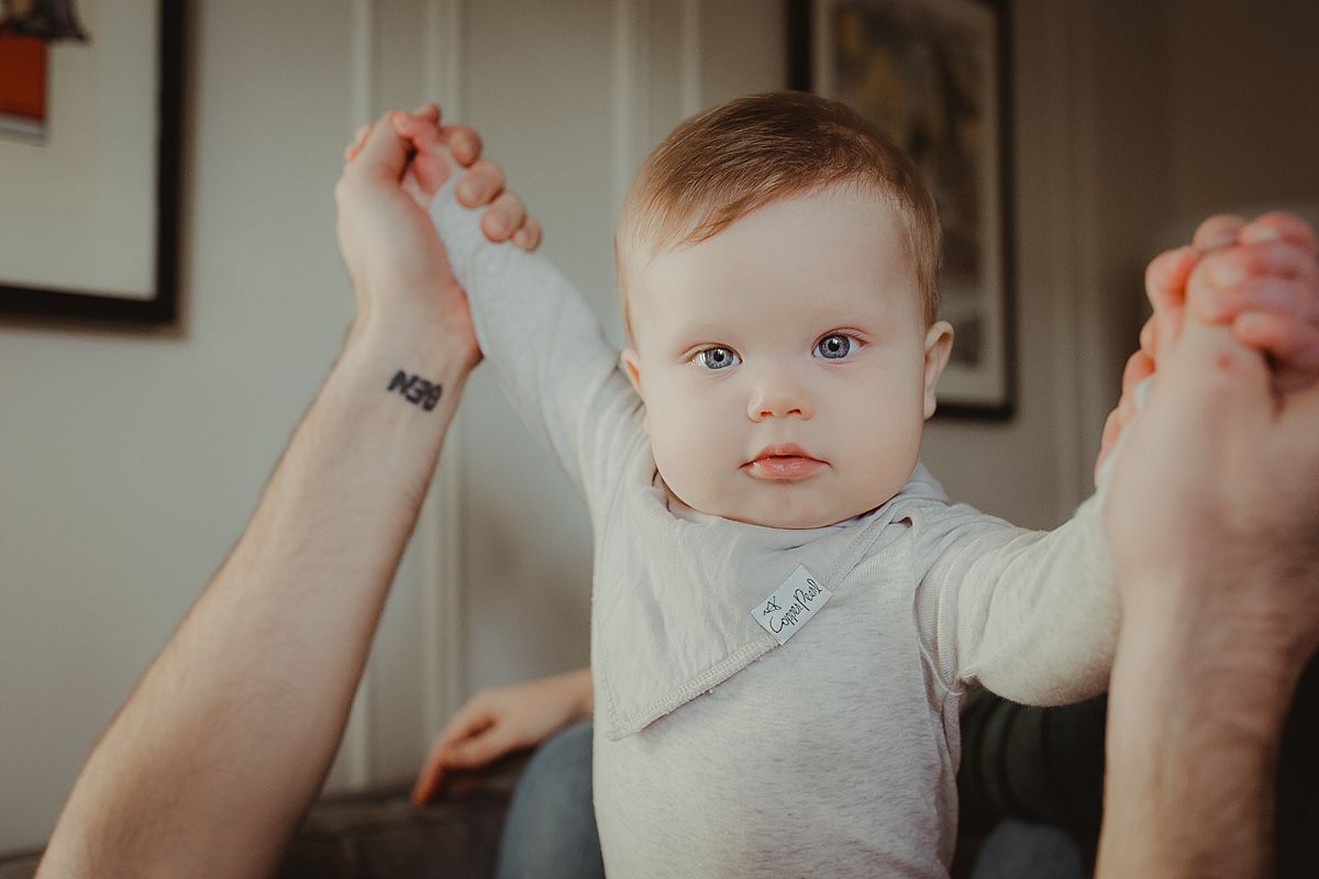 dad holds son's hands in the air while son looks eagerly at the camera. krystil mcdowall photography capturing candid family photos