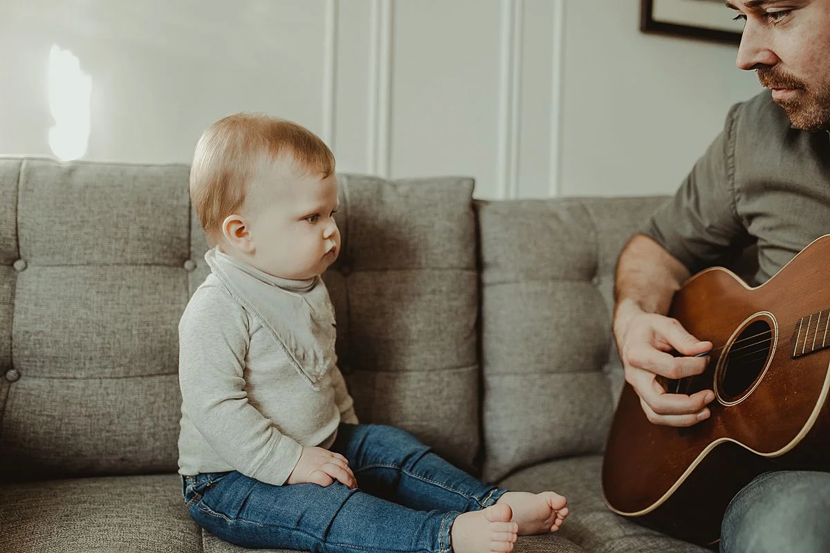 dad plays guitar while son watches curiously. capturing candid family moments to be treasured for a lifetime. krystil mcdowall photography