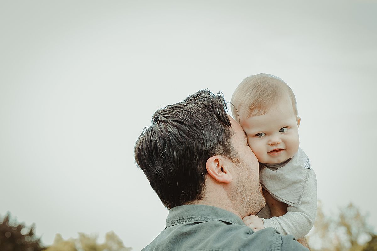 son enjoying cuddles with dad at local park in queens. image by photographer krystil mcdowall