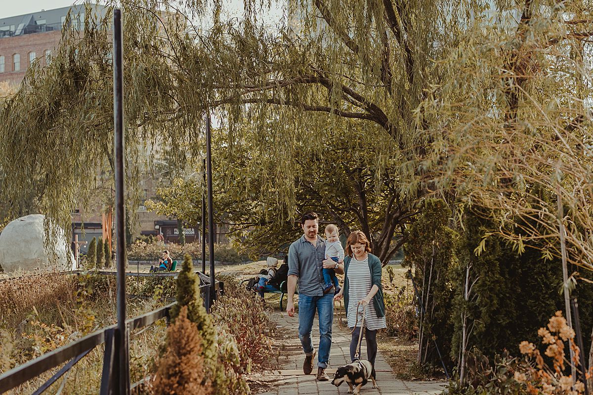 candid photo of family walking their dog at socrates sculpture park. image by nyc family and newborn photographer krystil mcdowall