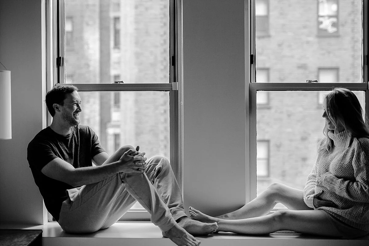 expecting mom and dad sit against windows in W hotel during maternity photoshoot with krystil mcdowall photography