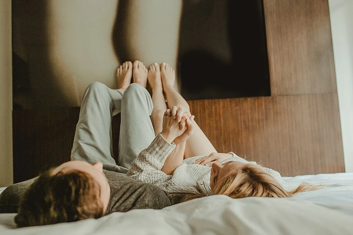 mom and dad's lay on hotel bed with feet against picture at the W hotel in nyc. image by nyc family photographer krystil mcdowall