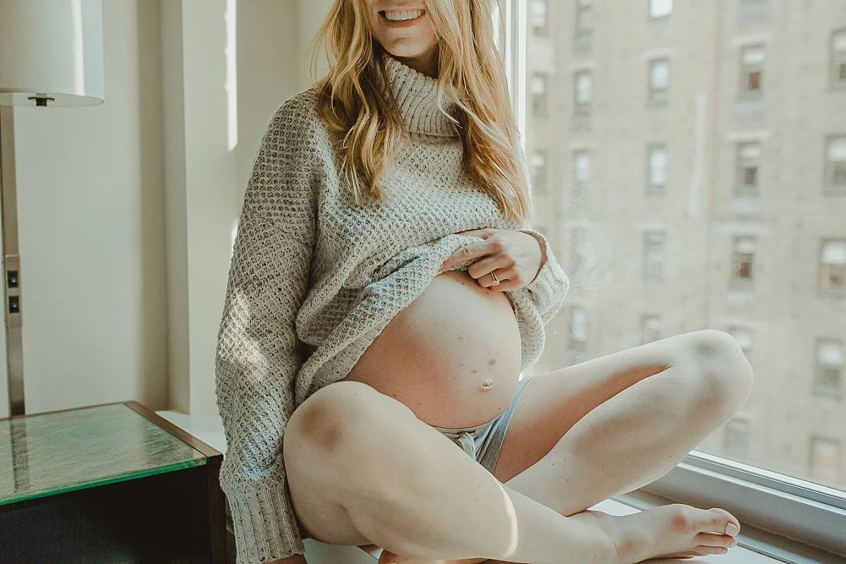 photo of mom exposing her big pregnant belly during lifestyle family photoshoot in midtown manhattan. photograhed by krystil mcdowall