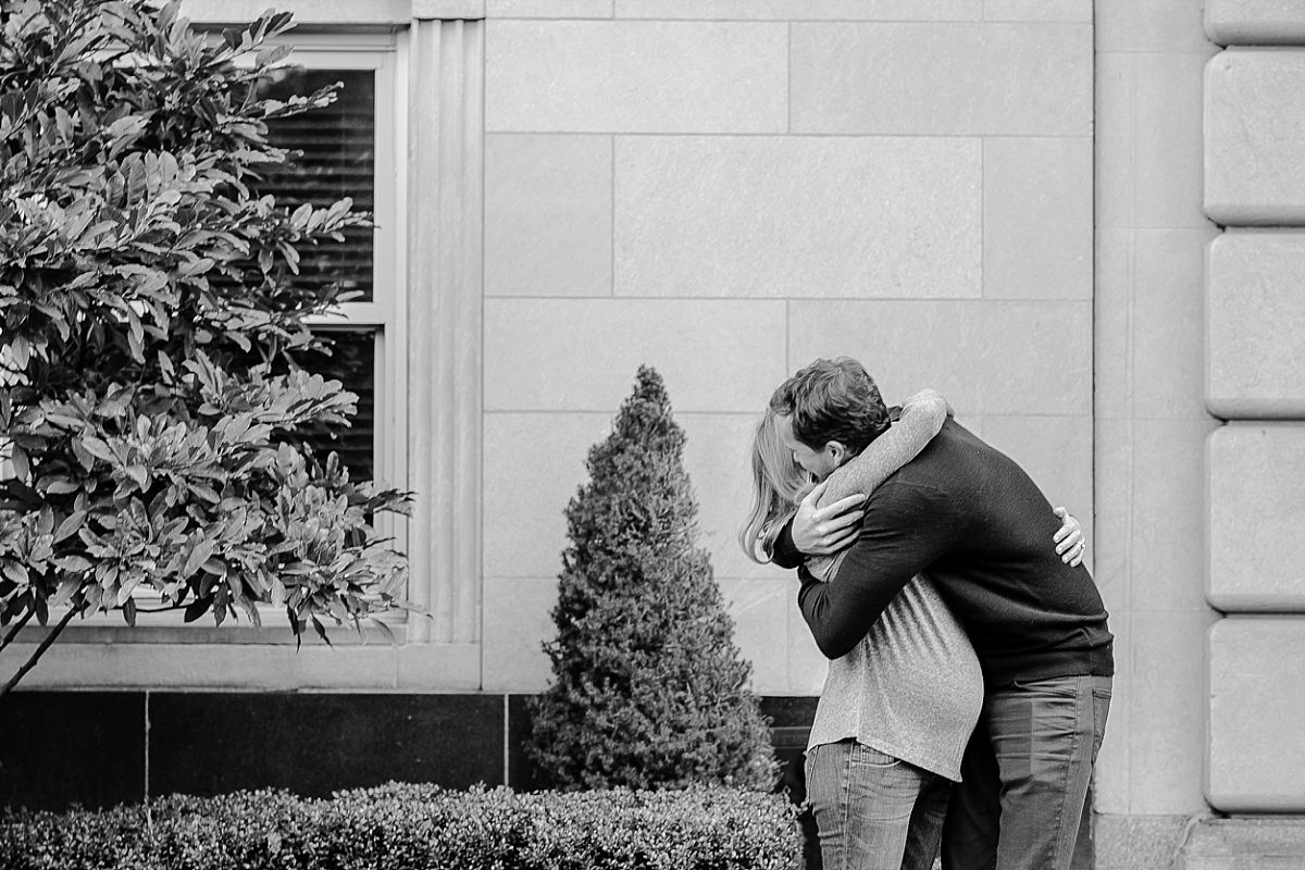 dad and mom hug on 5th avenue during lifestyle maternity photo session. image by nyc newborn and family photographer krystil mcdowall