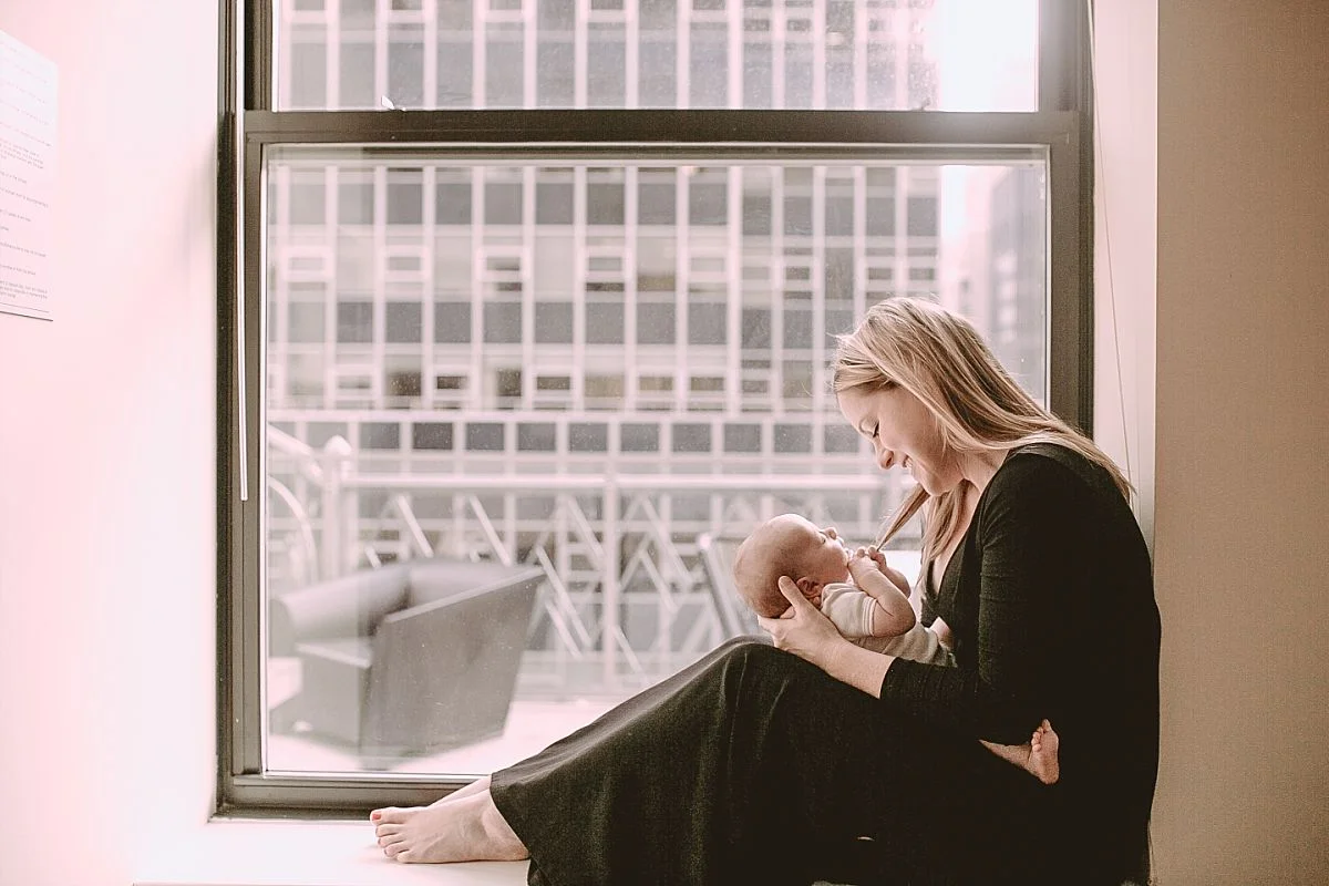 newborn daughter rests on mom's lap and plays with her hair. krystil mcdowall photography captures candid family moments