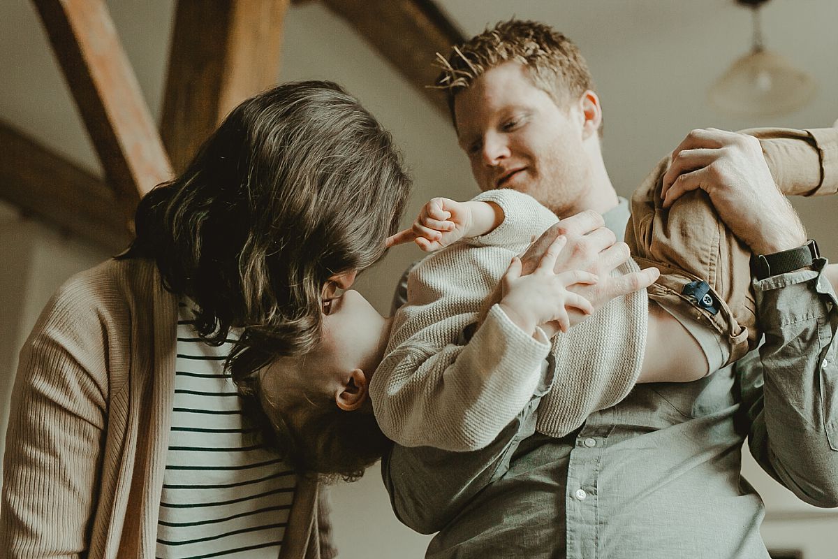 candid photo of mom and dad playing with son while he's hanging upside down. scapturing real candid moments for your family during documentary family photo session