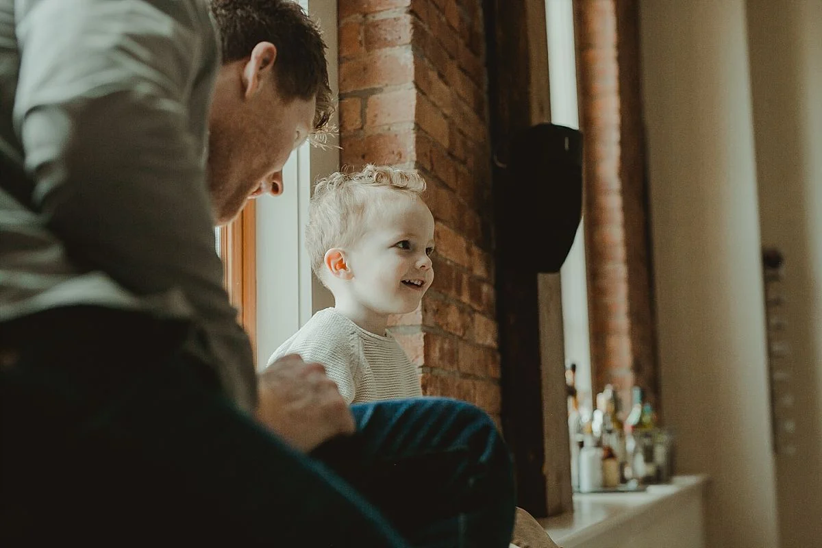 dad and son chilling on ledge near window of beautiful loft home. image by nyc family photographer krystil mcdowall