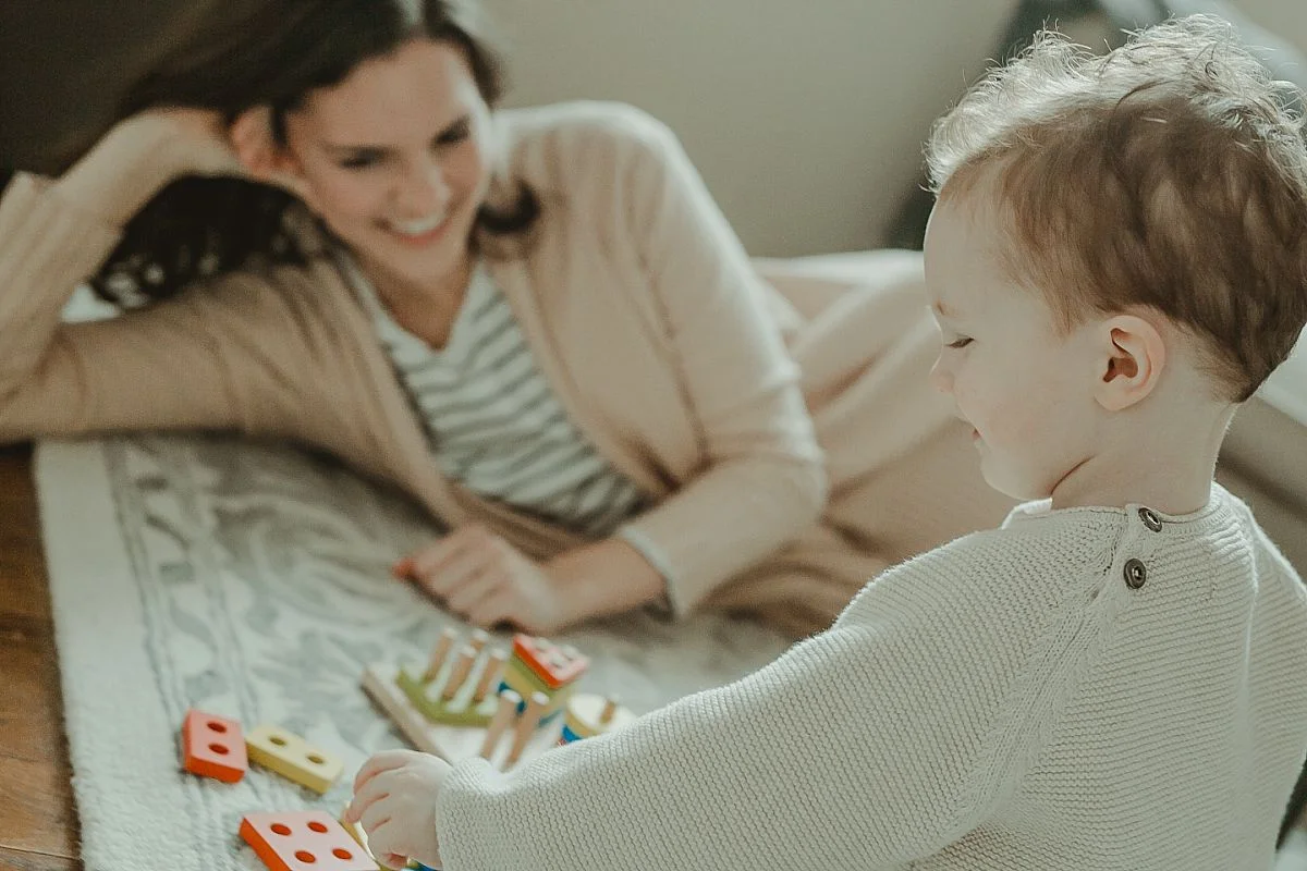 mom and son sit in living room together as son plays with shape sorter toy. krystil mcdowall captures candid moments for your family