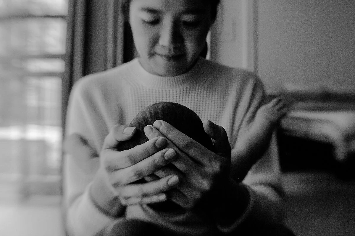 close up black and white photo of mom's hands as she holds newborn son in her arms. photo by krystil mcdowall photograhy