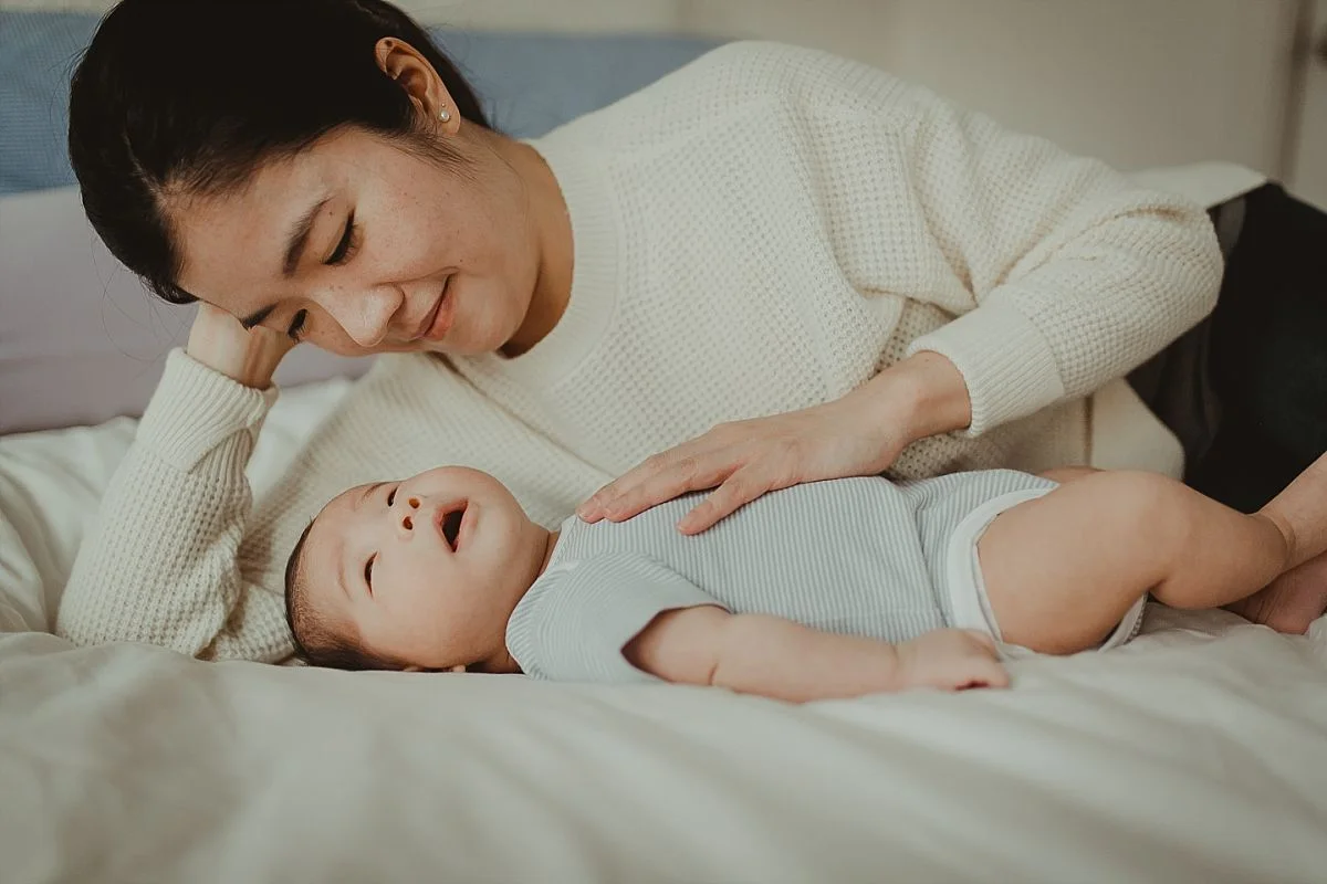 portrait of mom laying on her bed with newborn son. photo by nyc newborn photographer krystil mcdowall