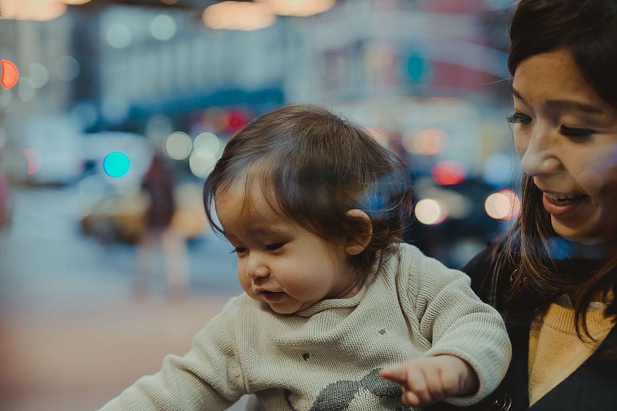 mom and daughter look at christmas ornaments on the streets of midtown manhattan during candid family photo session in nyc. image by nyc family photographer krystil mcdowall