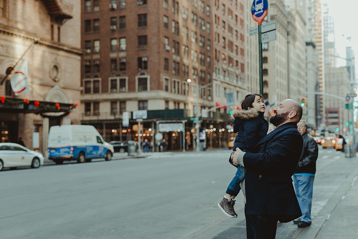dad and son exploring the streets and buildings of manhattan during candid family photo session in nyc. image by nyc family photographer krystil mcdowall