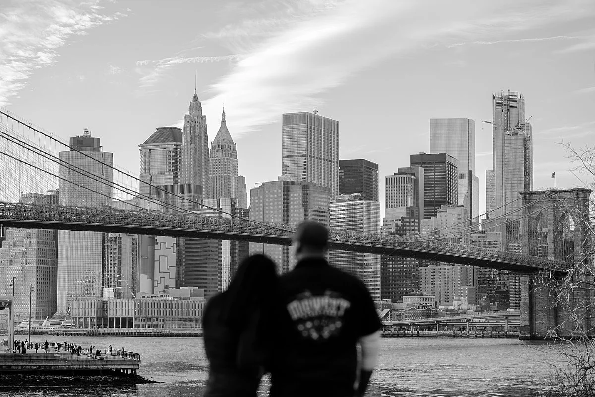 black and white image of blurred couple looking at beautiful manhattan skyline and brooklyn bridge. image by nyc family photographer krystil mcdowall
