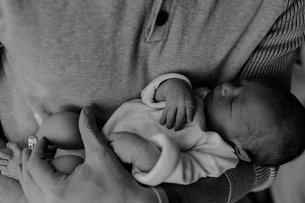 fresh 48 photo of newborn boy being held tightly in his dad's arms in his hospital room in nyc. photo by nyc family and newborn photographer krystil mcdowall