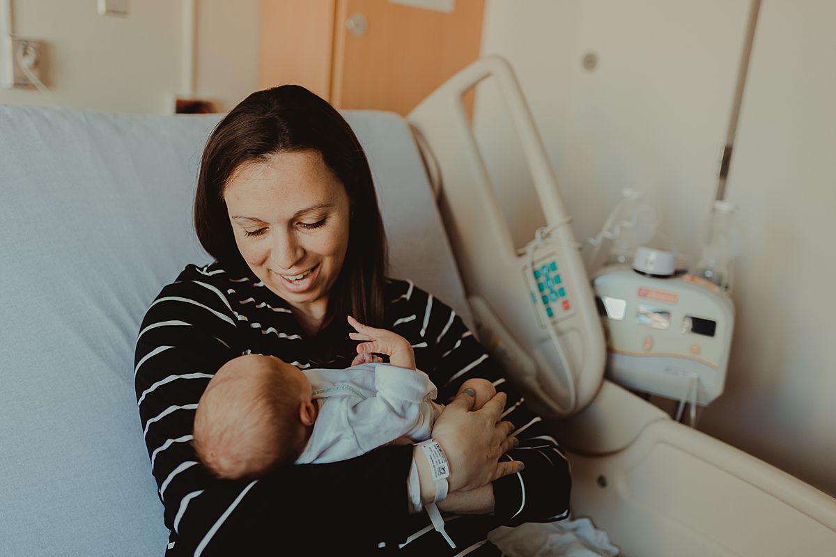fresh 48 photo of mom looking adoringly at her newborn baby boy while sitting in hospital bed in nyc. photo by nyc family and newborn photographer krystil mcdowall