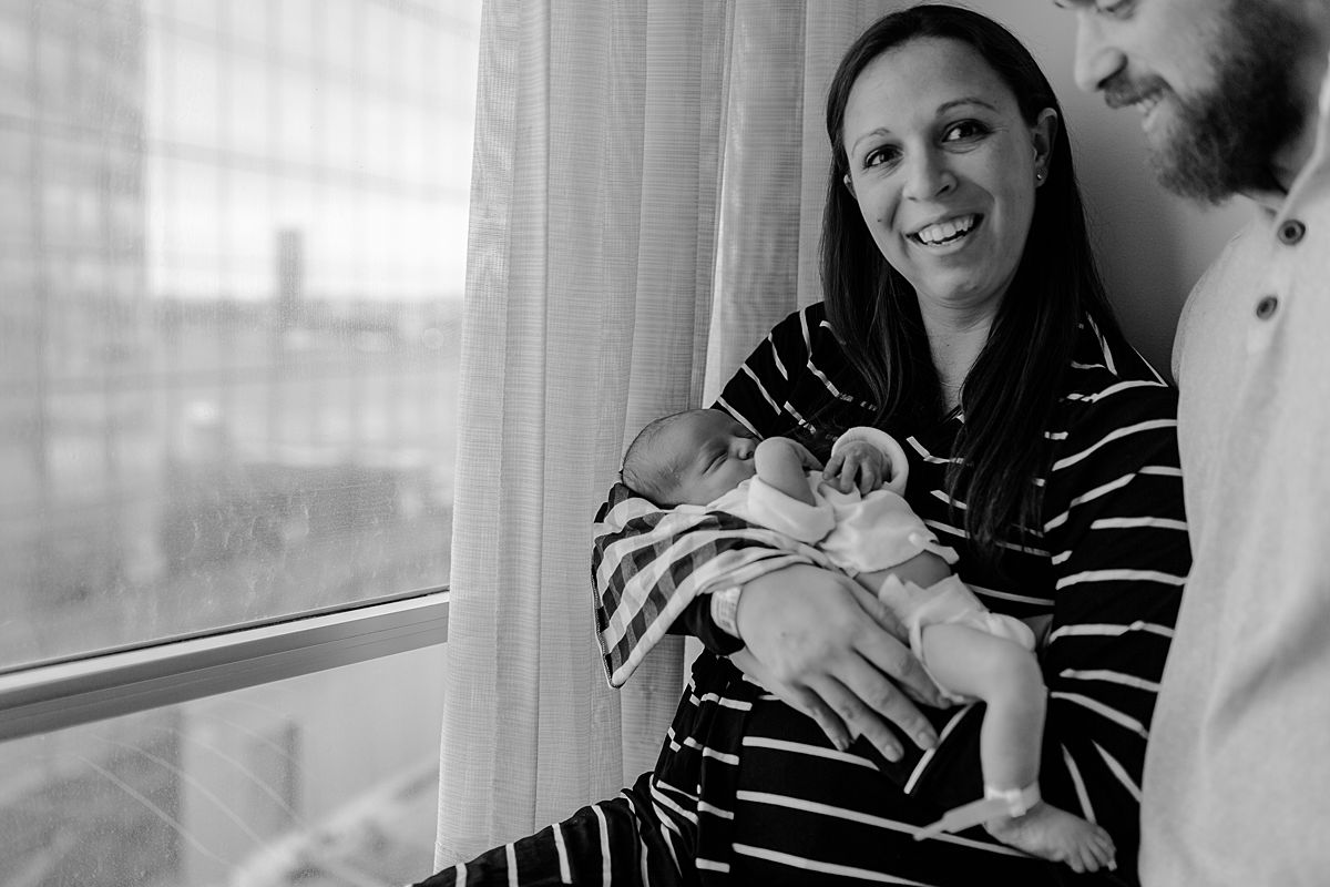candid fresh 48 photo of mom holding newborn son with dad onlooking in nyc hospital in manhattan. photo by nyc family and newborn photographer krystil mcdowall