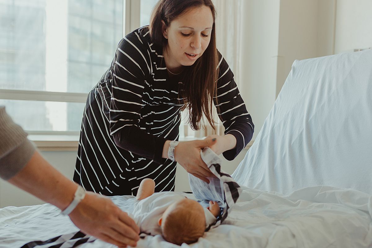 candid fresh 48 photo of mom swaddling newborn son in black and white swaddle. photo by nyc family and newborn photographer krystil mcdowall