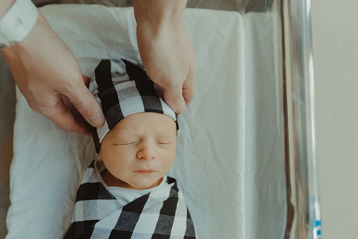 fresh 48 photo of dad holding newborn son's head as he sleeps in his hospital bassinet. photo by nyc family and newborn photographer krystil mcdowall