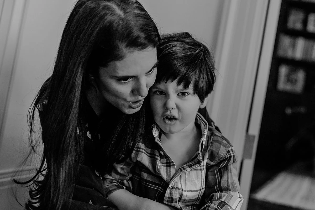 son sitting on mom's lap and making funny faces together. Capturing real family moments NYC family photographer Krystil McDowall