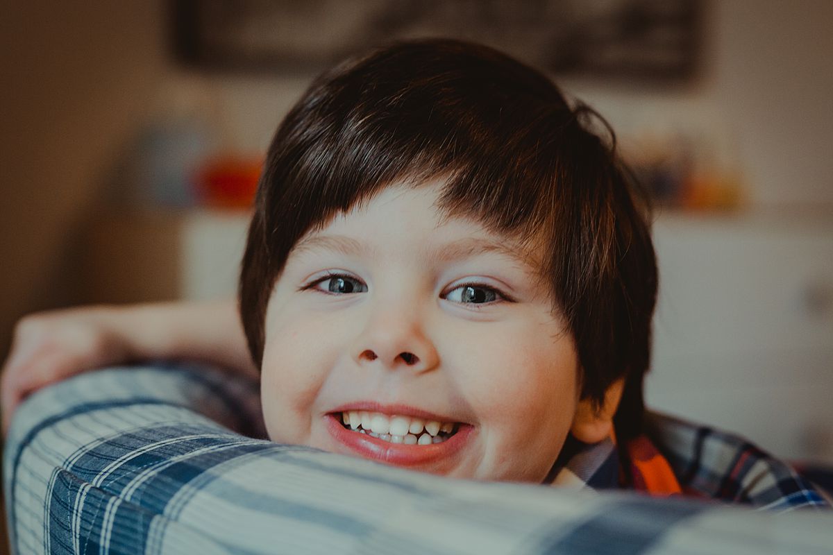 young boy in room of nyc apartment with big small big blue eyes and smiling at the camera. photo by nyc family and newborn photographer Krystil McDowall
