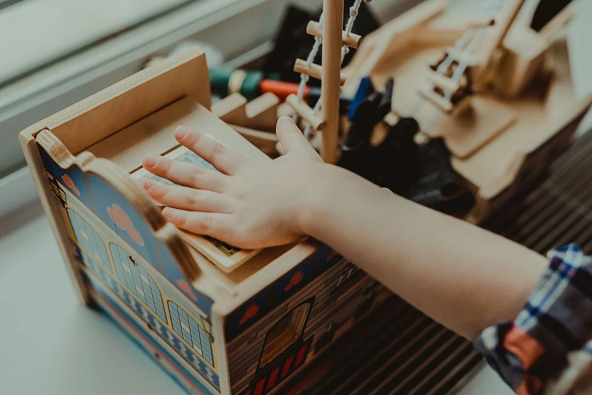 close up detail shot of young boy in room of nyc apartment playing with wooden ship toy. photo by nyc family and newborn photographer Krystil McDowall