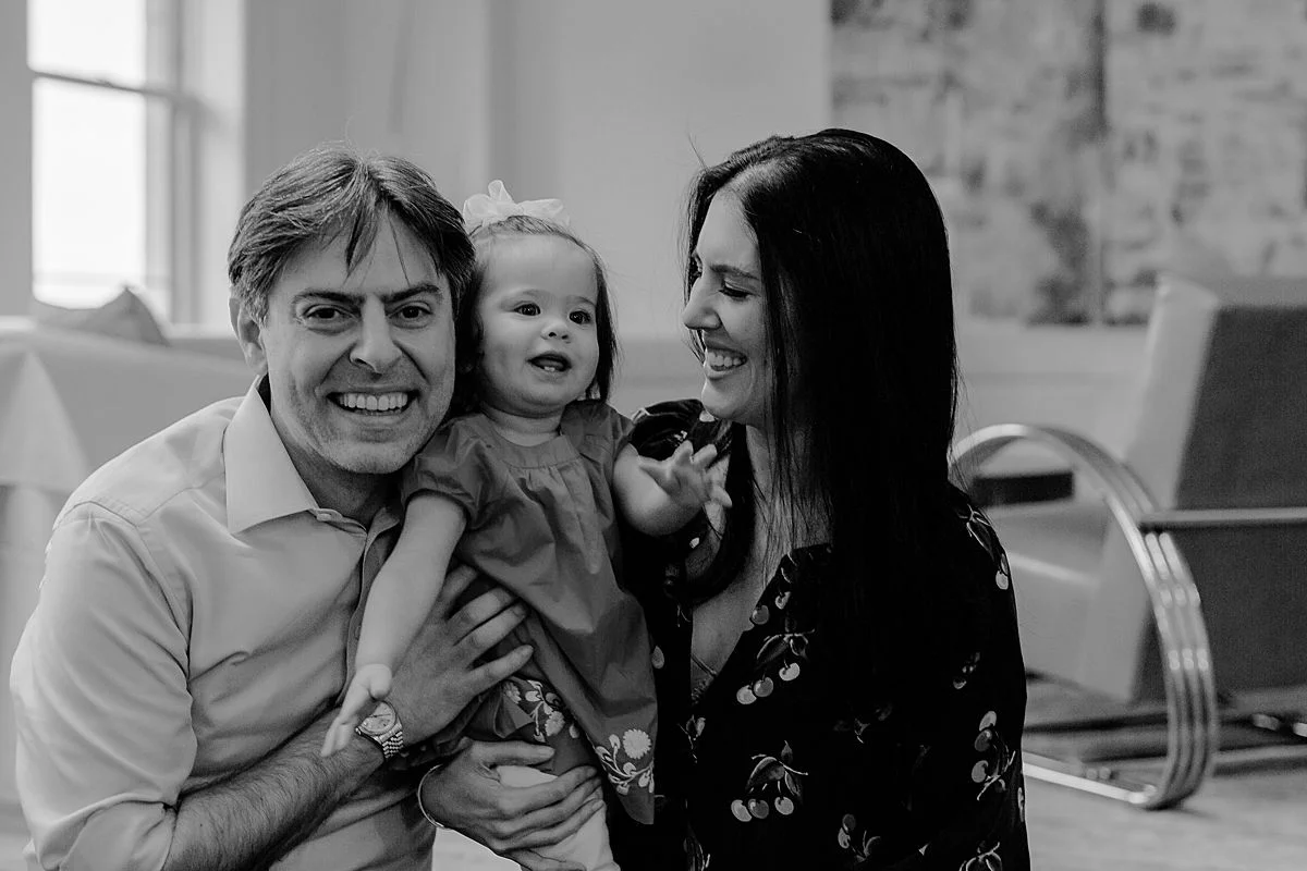 candid black and white family portrait of mom, dad and daughter playing in living room of nyc apartment. photo by nyc family and newborn photographer Krystil McDowall
