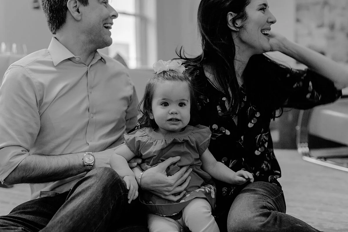 candid black and white family portrait of mom, dad and daughter playing in living room of nyc apartment. photo by nyc family and newborn photographer Krystil McDowall
