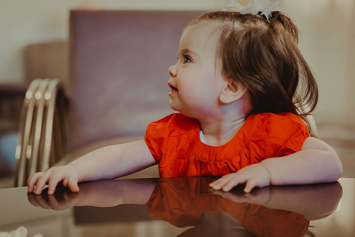 portrait of one year old daughter in red dress playing in living room of nyc apartment. photo by nyc family and newborn photographer Krystil McDowall