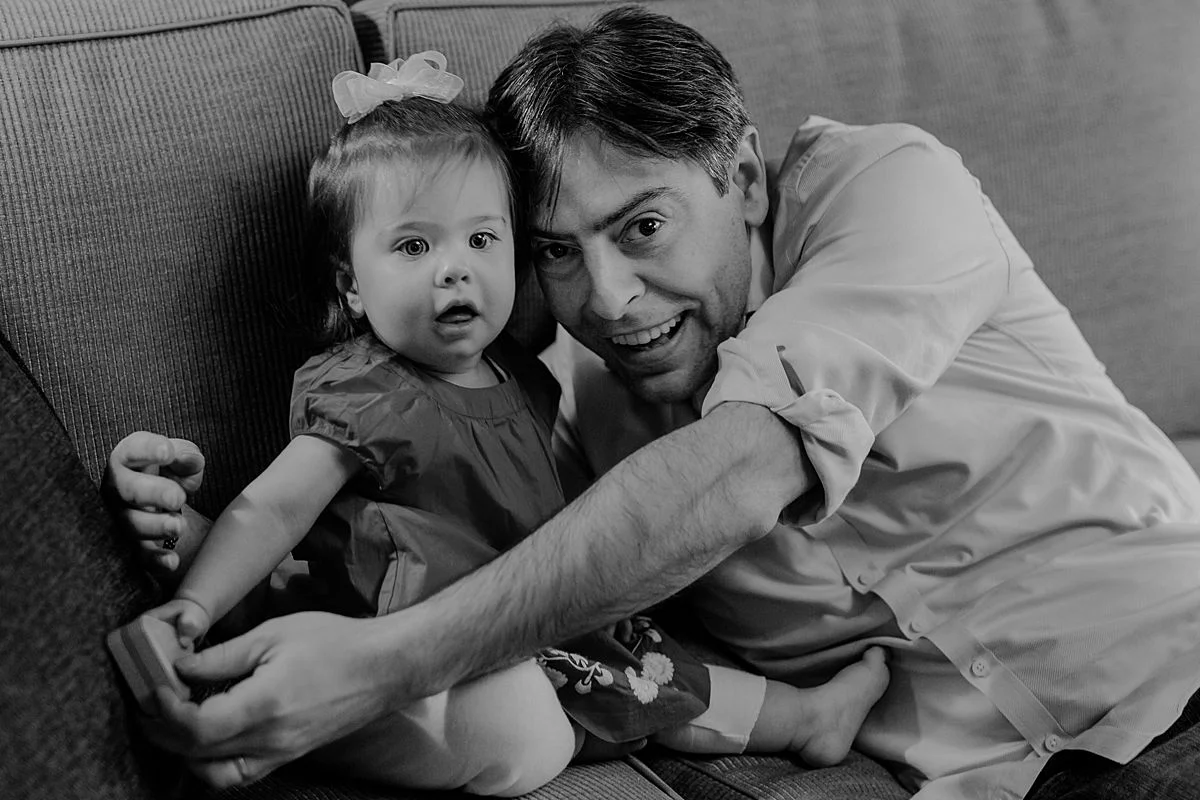 candid portrait of dad and one year old daughter playing playing with wooden toys on living room couch. photo by nyc family and newborn photographer Krystil McDowall