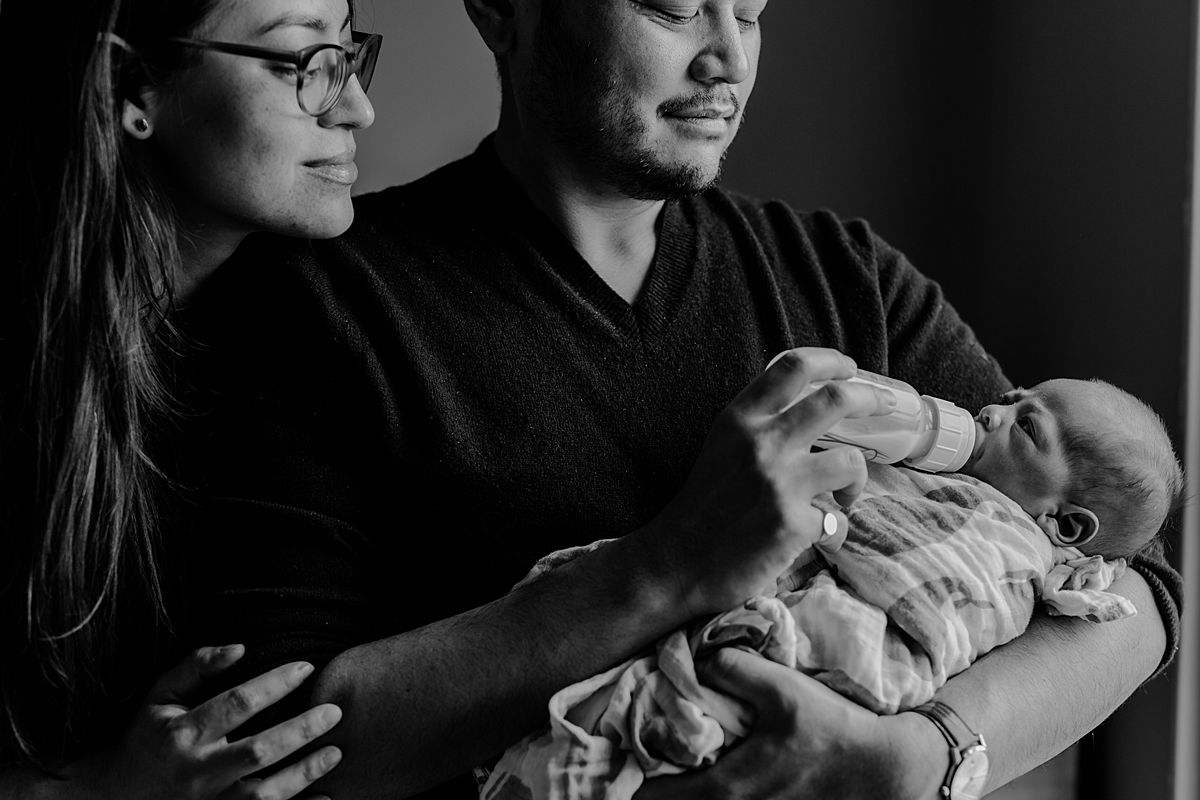 photo of mom and dad feeding newborn boy in nyc apartment. photo by nyc family and newborn photographer krystil mcdowall