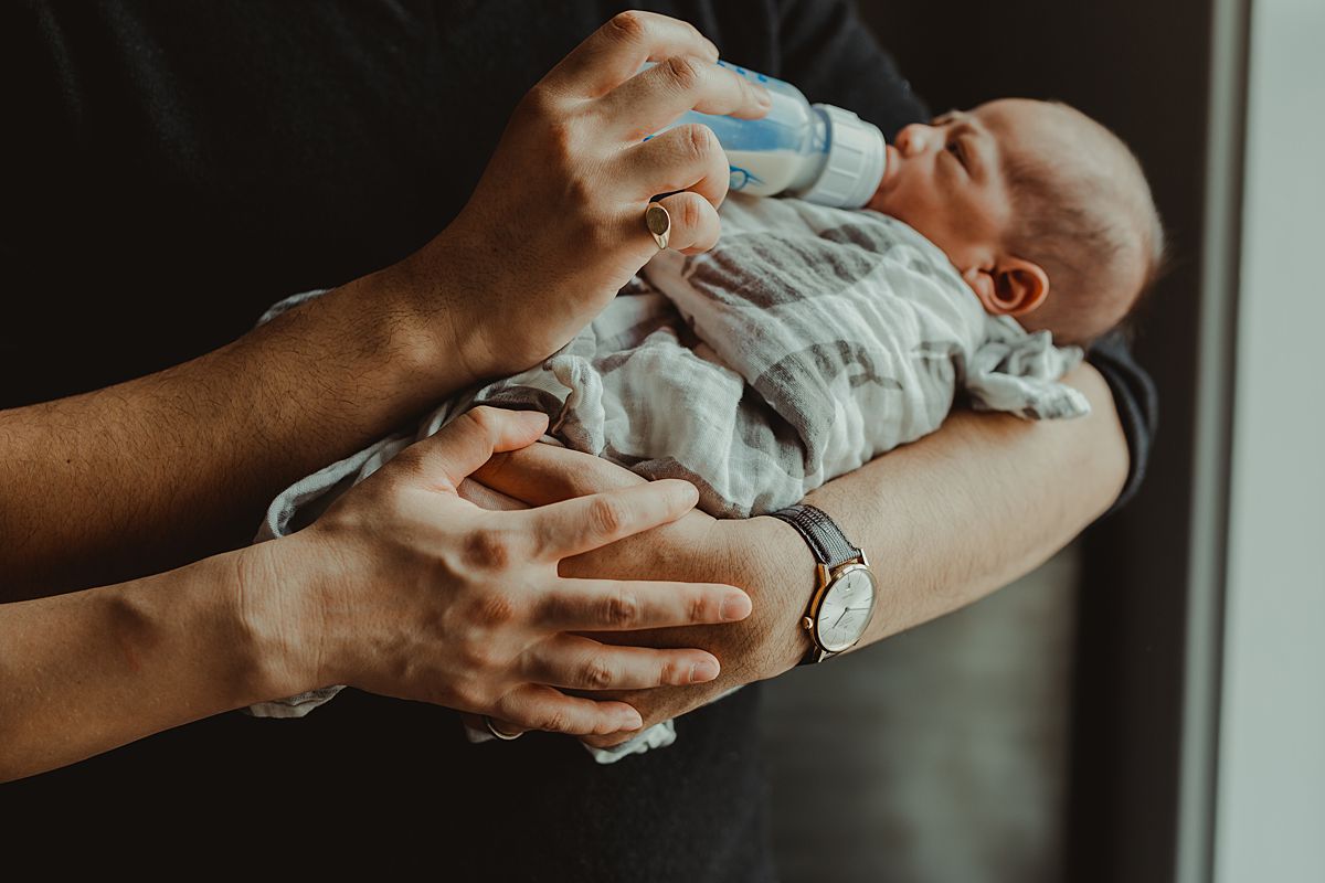 close up photo of mom and dad's hands as they hold and feed newborn boy. photo by nyc family and newborn photographer krystil mcdowall
