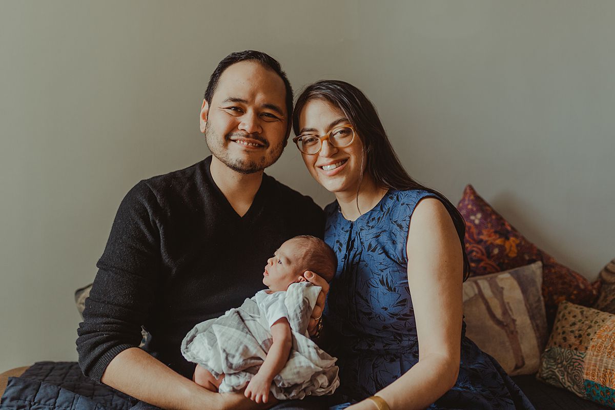 first family portrait of family of three sitting couch in nyc lounge room. photo by nyc family and newborn photographer krystil mcdowall