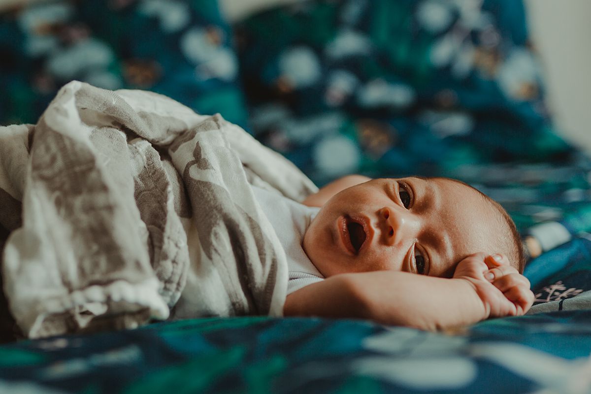 photo of newborn son yawning as he wakes from a sleep on mom and dad's bed. photo by nyc family and newborn photographer krystil mcdowall