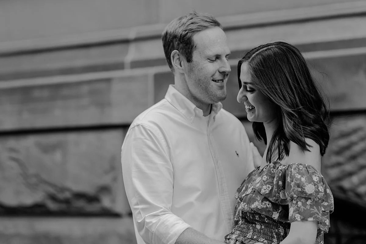 black and white portrait of expecting couple standing in front of The Dakota on central park west nyc for maternity photo session. maternity photo by nyc family and newborn photographer krystil mcdowall