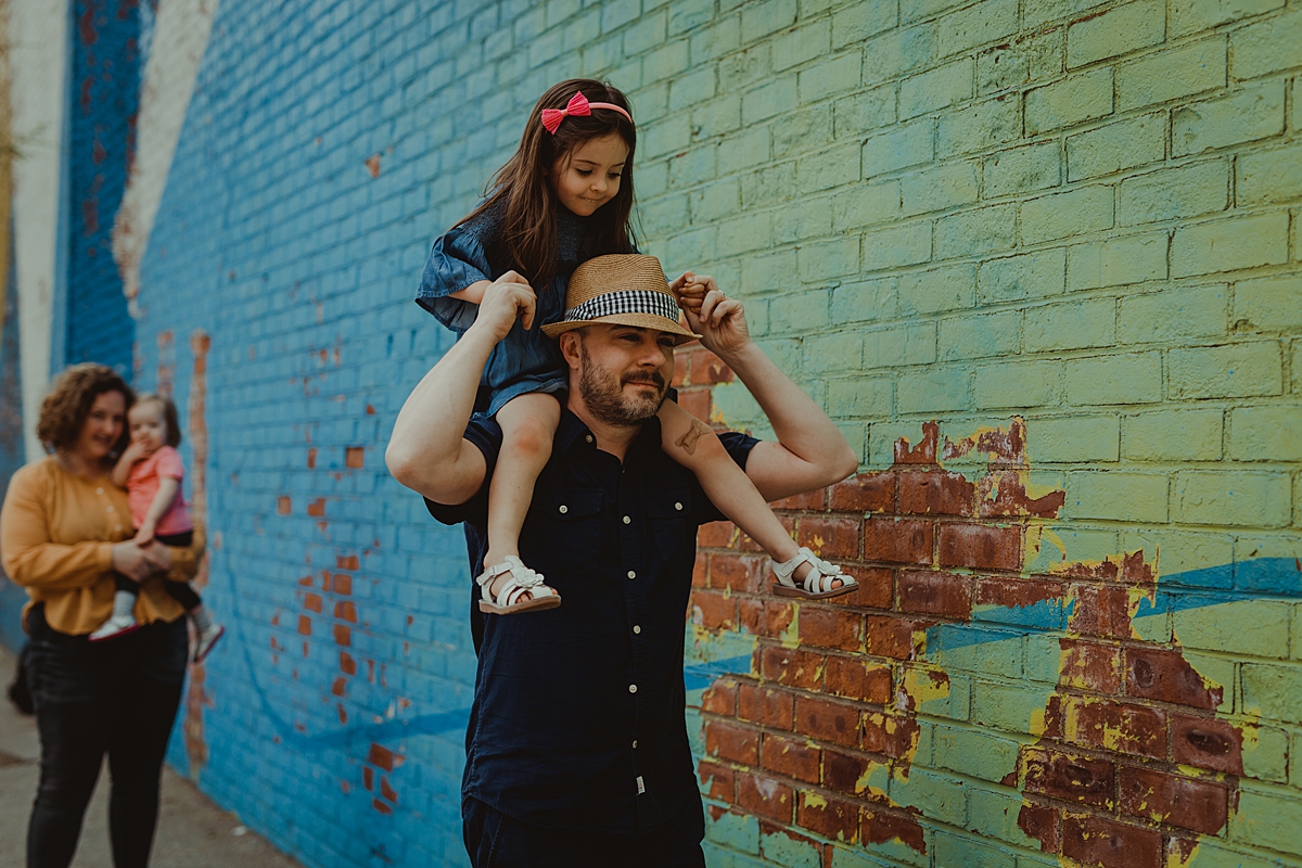 photo of family strolling in front of bright and colorful graffiti wall in dumbo brooklyn. photo by nyc family and newborn photographer krystil mcdowall