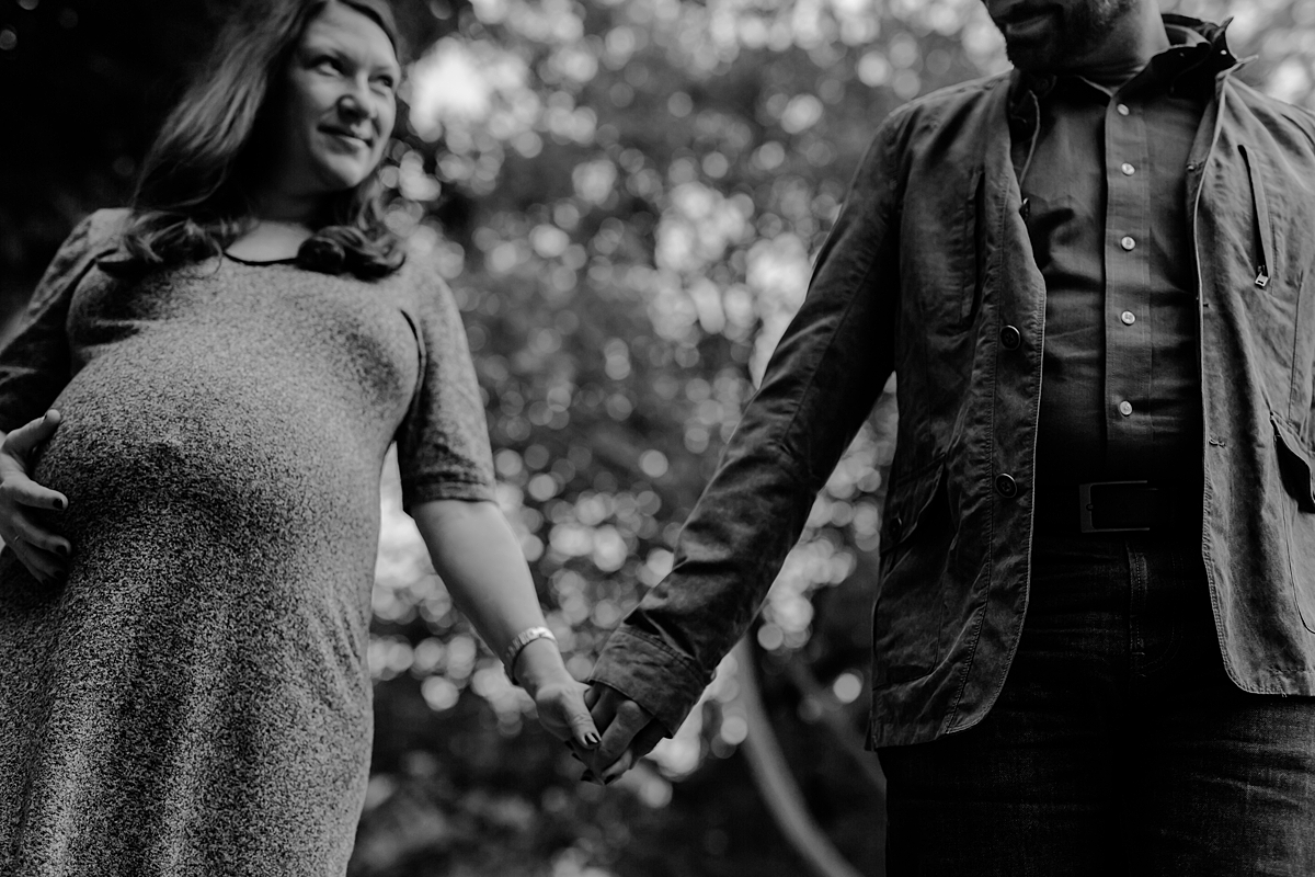 image of expecting husband and wife holding hands walking in stuyvesant square park during outdoor maternity photo session in new york city. photo by nyc family and newborn photographer krystil mcdowall
