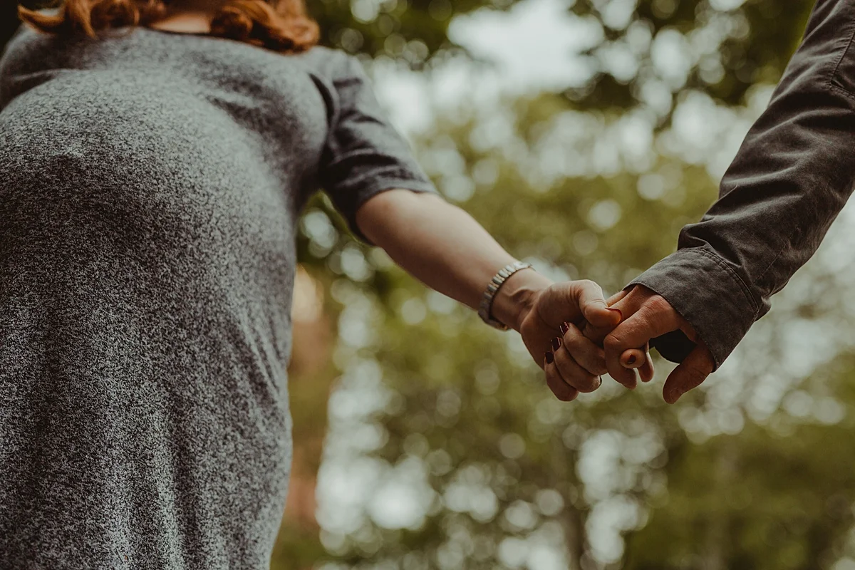 image of expecting husband and wife holding hands walking in stuyvesant square park during outdoor maternity photo session in new york city. photo by nyc family and newborn photographer krystil mcdowall