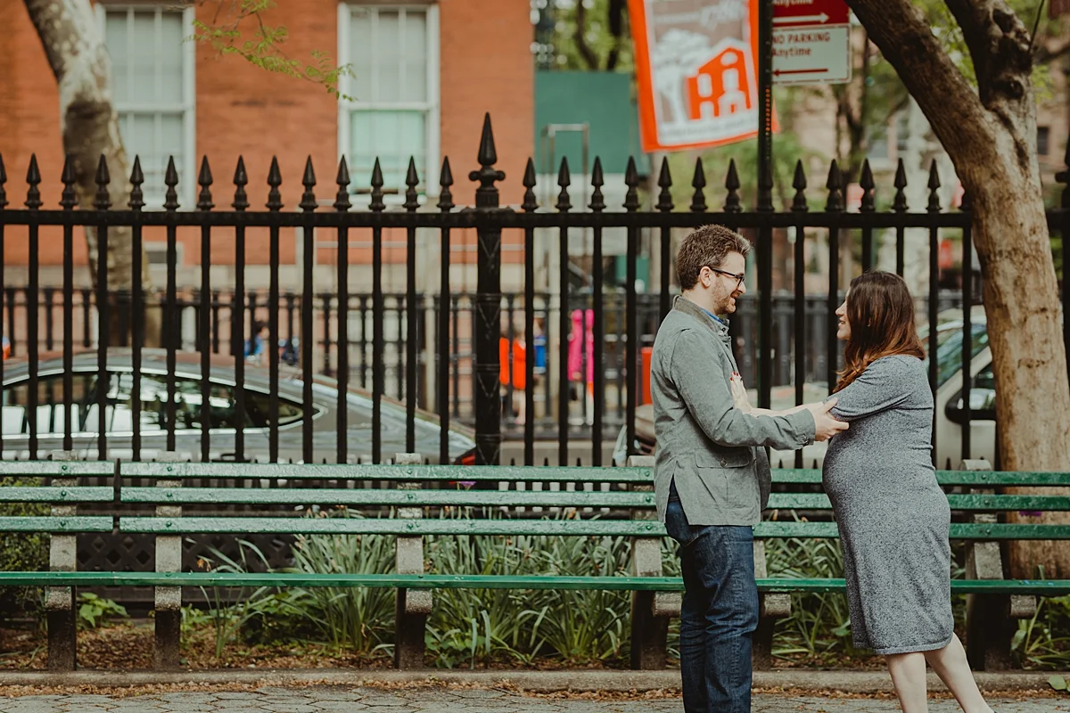 candid photo of pregnant husband and wife in stuyvesant square park during their nyc maternity photo session. photo by nyc family and newborn photographer krystil mcdowall